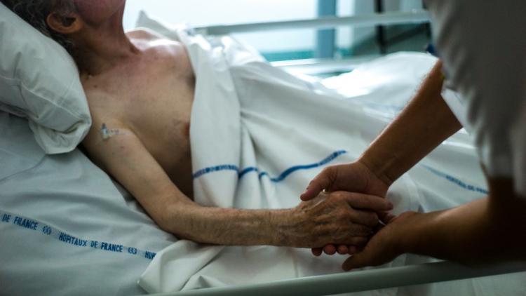 Une infirmière tient la main d'un patient dans une unité de soins palliatifs d'Argenteuil, le 22 juillet 2013 [FRED DUFOUR / AFP/Archives]