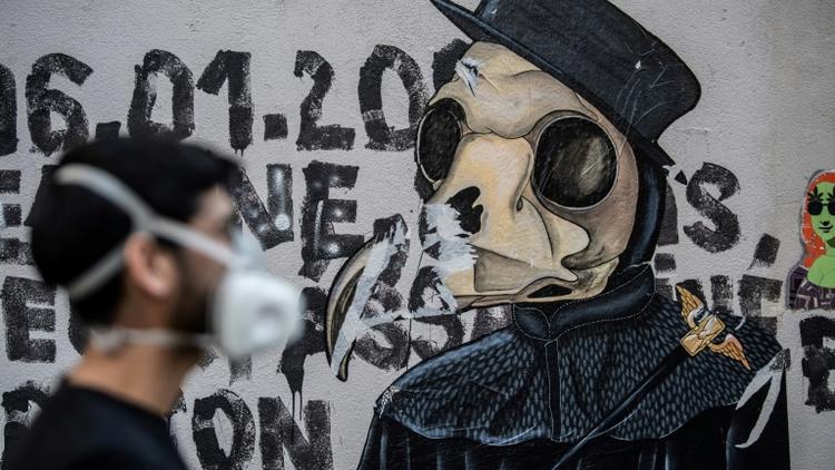 L'artiste Angel Crow devant une de ses oeuvres, dans une rue à Paris, le 22 avril 2020 [Martin BUREAU / AFP]