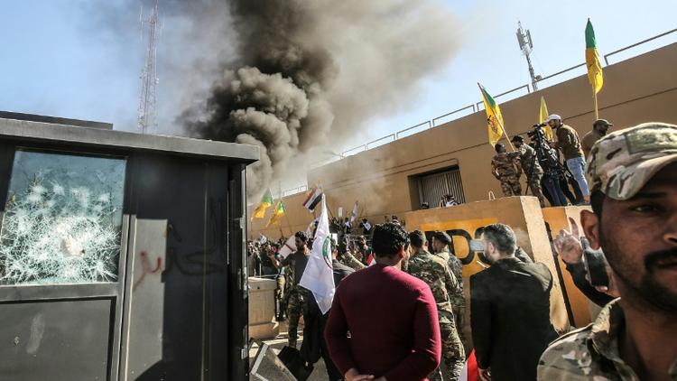 Des membres et partisans du Hachd al-Chaabi, coalition de paramilitaires dominée par des factions pro-Iran, incendient une tourelle devant l'ambassade des Etats-Unis à Bagdad le 31 décembre 2019 [Ahmad AL-RUBAYE / AFP]