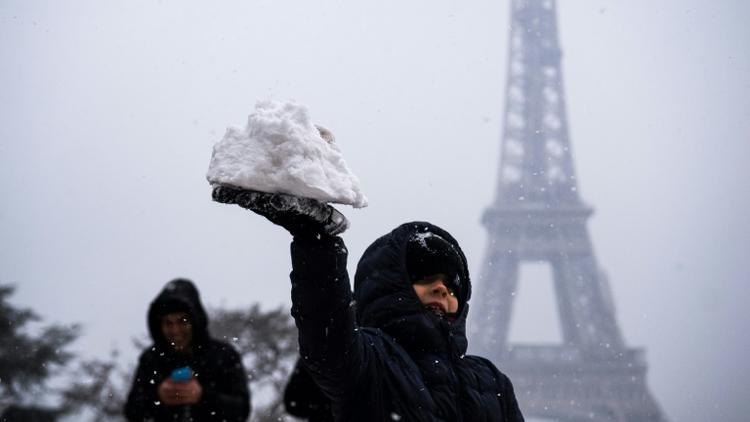 Un enfant joue avec de la neige devant la Tour Eiffel, le 5 février 2018 à Paris. [Lionel BONAVENTURE / AFP/Archives]
