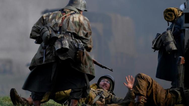 Un acteur en uniforme allemand de la Seconde Guerre mondiale lors d'une scène de capture de soldats américains durant une reconstitution de la bataille des Ardennes, à Hardigny (Belgique) le 15 décembre 2019 [JOHN THYS / AFP]