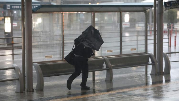 Un homme s'abrite des fortes précipitations causées par le typhon Trami à Kagoshima (sud-ouest du Japon) le 30 septembre 2018. [Behrouz MEHRI / AFP]