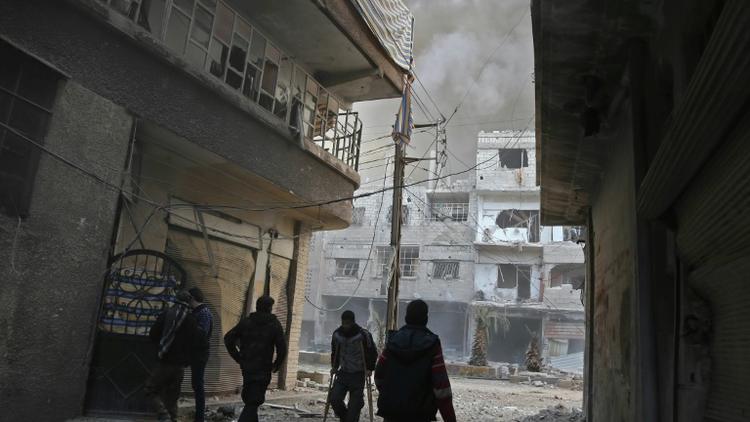 Des colonnes de fumée et de la poussière s'élèvent de la localité de Hammouriyé dans le fief rebelle de la Ghouta orientale près de Damas, après un raid du régime, le 21 février 2018 [ABDULMONAM EASSA / AFP]