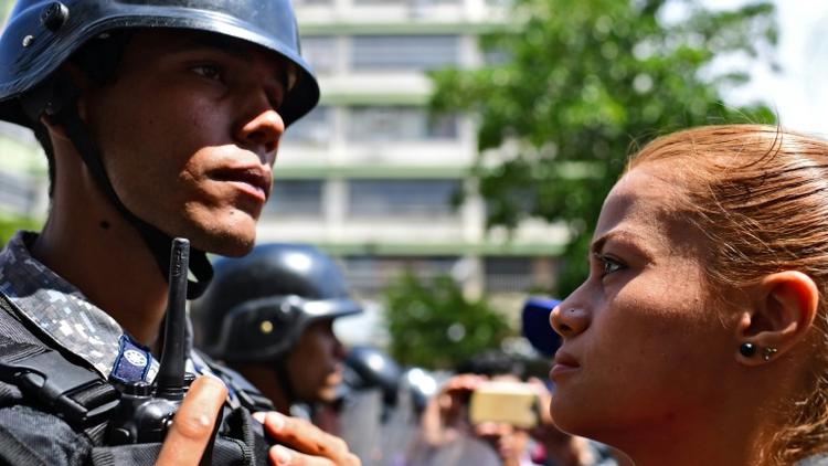 Une partisane du président autoproclamé vénézuelien Juan Guaido fait face à un policier lors d'une manifestation à Caracas le 9 mars 2019 [RONALDO SCHEMIDT / AFP]