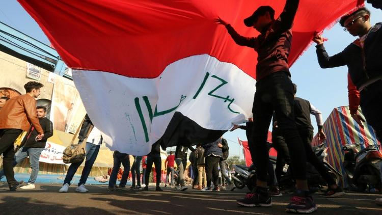 Des manifestants irakiens soulèvent un drapeau sur la place Tahrir à Bagdad, le 22 décembre 2019 [SABAH ARAR / AFP]