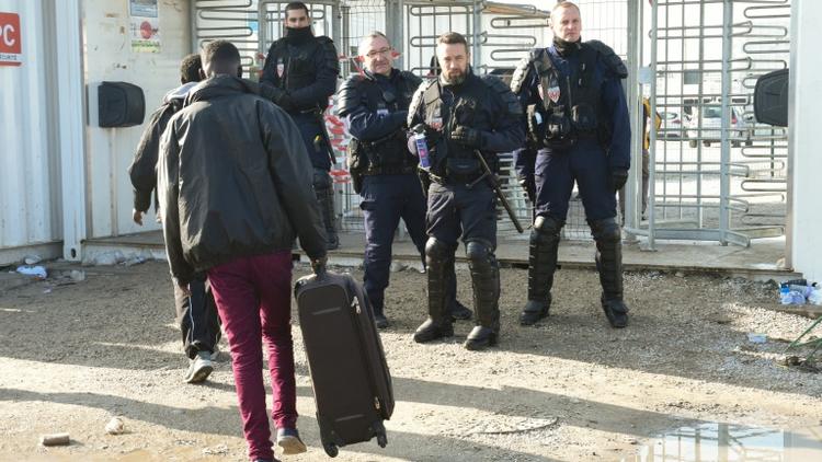 Un migrant se dirige vers des policiers à l'entrée de la "Jungle" de Calais, le 23 octobre 2016 [FRANCOIS LO PRESTI                   / AFP]