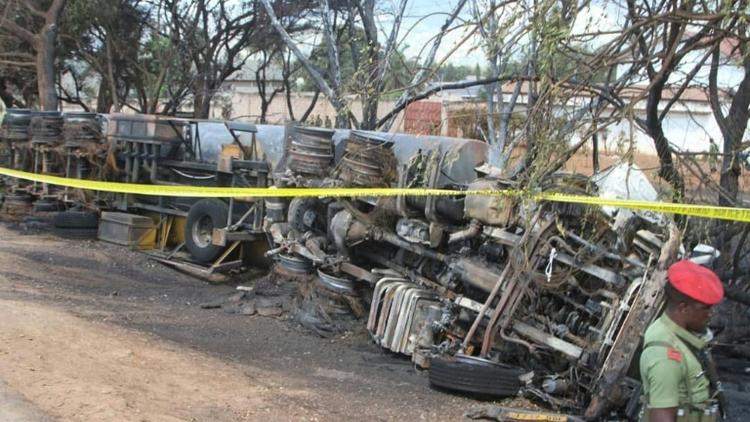 Un membre des forces de sécurité tanzanienne surveille la carcasse d'un camion-citerne accidenté, dont l'explosion a fait plus de 60 morts parmi les passants qui tentaient de le siphonner, le 10 août 2019, à Morogoro.  [STRINGER / AFP]