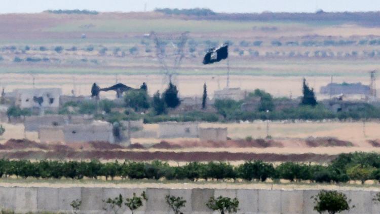 Un drapeau du groupe Etat islamique aperçu près de la frontière entre la Turquie et la Syrie, le 7 mai 2016 [ILYAS AKENGIN / AFP/Archives]