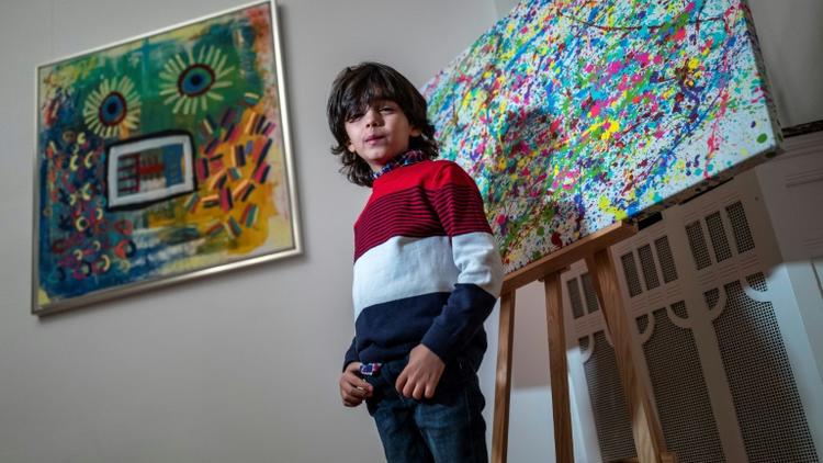 L'artiste allemand de 7 ans Mikail Akar pose devant ses peintures «Champi» et «Homme tournesol» avant l'ouverture de son exposition «Manus 11» à Berlin, le 13 décembre 2019.