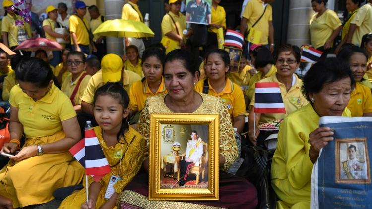 Des Thaïlandaises tiennent le portrait du roi Maha Vajiralongkorn, près du Grand palais, en attendant la grande parade pour son couronnement dans les rues de Bangkok, le 5 mai 2019 [Lillian SUWANRUMPHA / AFP]