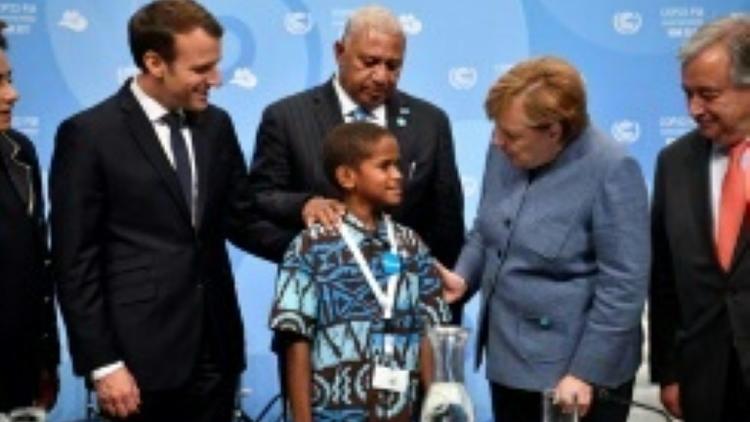Timoci Naulusala un petit fidjien est félicité par le président Emmanuel Macron (g) et la chancelière Angela Merkel après son discours devant la COP 23 à Bonn [ / AFP]
