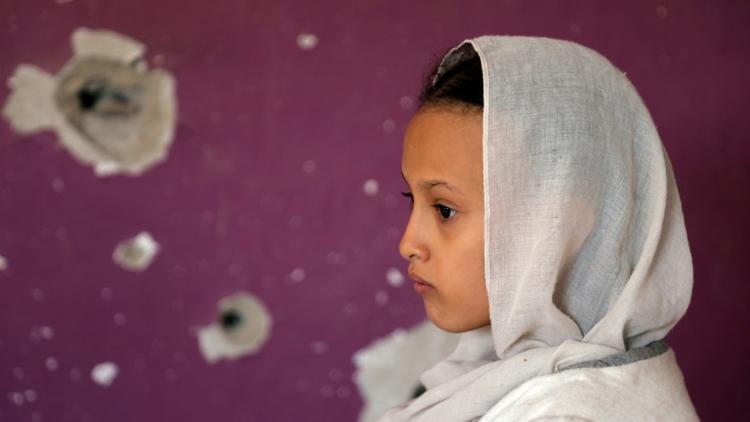 Une jeune fille yéménite, devant un mur criblée de balles, à Taez (Yémen), le 30 septembre 2018 [Ahmad AL-BASHA / AFP/Archives]