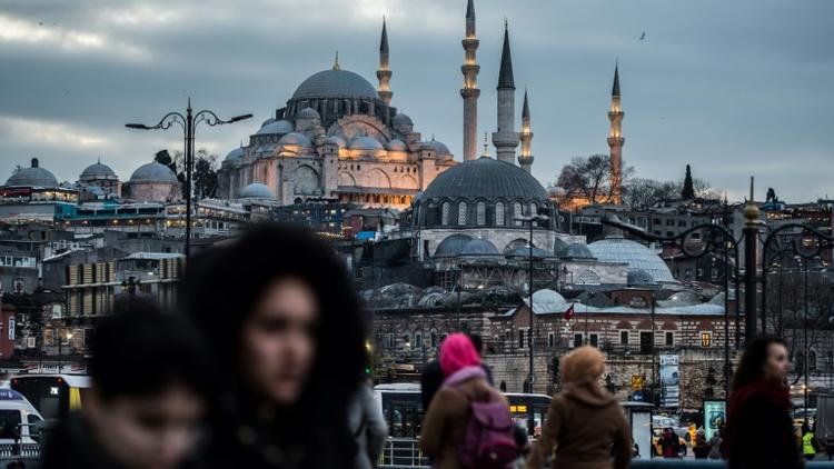 Des piétons traversent le pont de Galata à Istanbul, le 27 janvier 2018, avec la mosquée de Suleymaniye en arrière-plan [YASIN AKGUL / AFP/Archives]