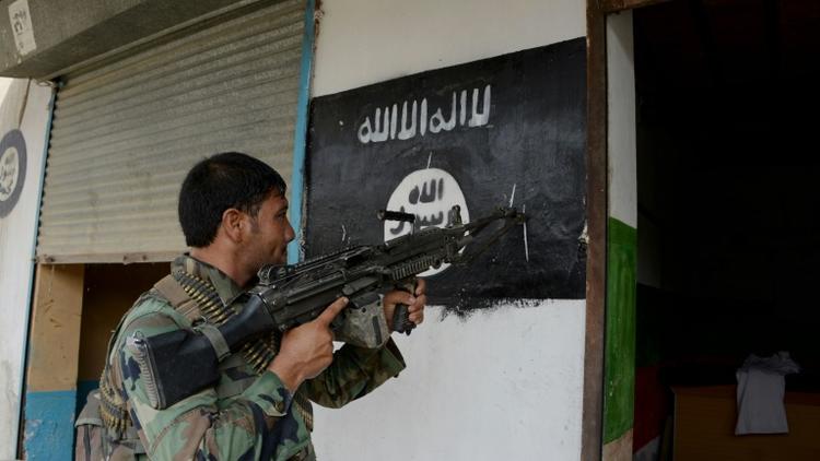 Un soldat de l'armée afghane pointe son arme sur un drapeau du groupe Etat islamique peint sur un mur à Kot, dans l'est de l'Afghanistan, le 26 juillet 2016 [NOORULLAH SHIRZADA / AFP/Archives]