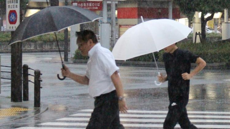 Des piétons sous la pluie à Tokushima au Japon, le 23 août 2018 [JIJI PRESS / JIJI PRESS/AFP]