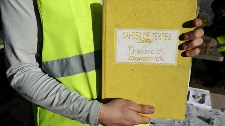 Un "gilet jaune" montre le cahier de doléances qu'il présente sur un rond-point à Cagnes-sur-mer, le 20 décembre 2018 [VALERY HACHE / AFP/Archives]