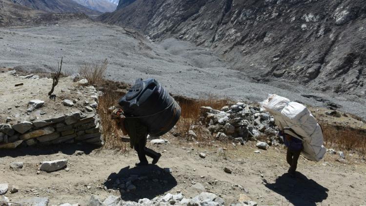 Des porteurs avec différents matériaux sur le dos qui doivent servir à reconstruire le village de  Langdang au Népal, le 6 avril 2016 [PRAKASH MATHEMA / AFP]