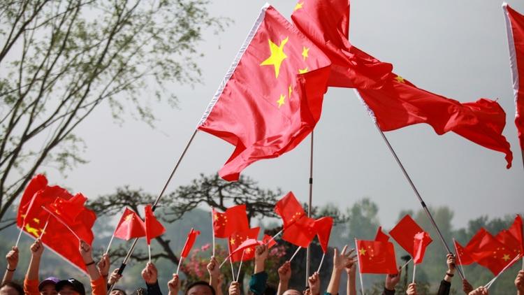 Des Chinois agitent des drapeaux et entonnent des chants patriotiques lors de la commémoration des 70 ans de la République populaire de Chine, le 18 avril 2019 [STR / AFP]