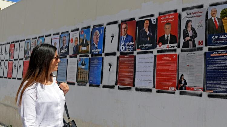 Une Tunisienne passe devant des affiches de campagne des candidats à la présidentielle, le 7 septembre 2019 à Tunis [FETHI BELAID / AFP/Archives]