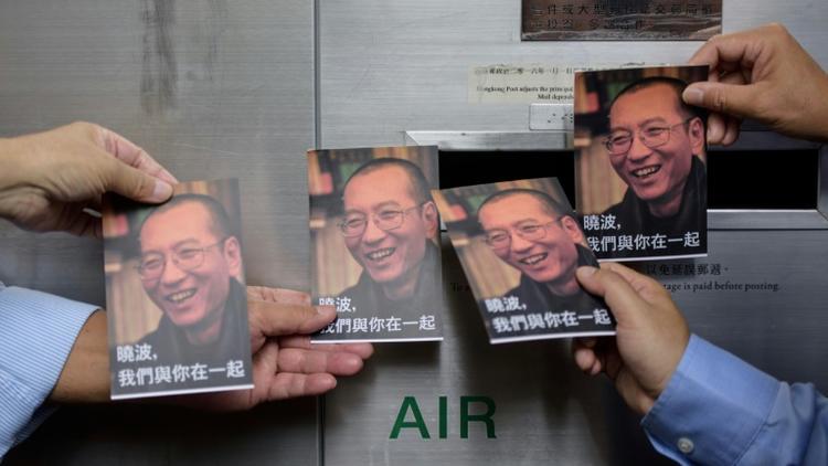 Des manifestants brandissent des cartes à l'effigie du dissident chinois Liu Xiaobo, le 5 juillet 2017 à Hong Kong [Anthony WALLACE / AFP/Archives]