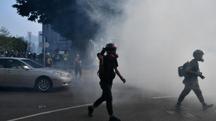 Des photographes fuient les gaz lacrymogènes tirés par la police, à Hong Kong le 27 octobre 2019 [Anthony WALLACE / AFP]
