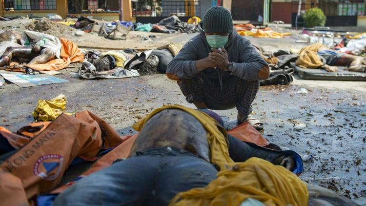 Un survivant du tsunami devant le corps de sa femme retrouvé parmi des dépouilles, le 2 octobre 2018 à Palu, ville indonésienne frappée par un séisme et un tsunami [BAY ISMOYO / AFP]