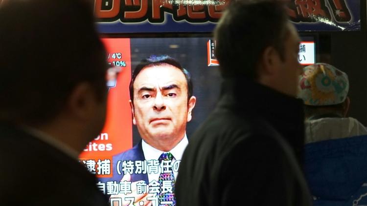 Des piétons passent devant un écran de télévision sur lequel apparaît le visage de Carlos Ghosn, ex-PDG de Nissan, le 21 décembre 2018 à Tokyo, au Japon [Kazuhiro NOGI / AFP/Archives]