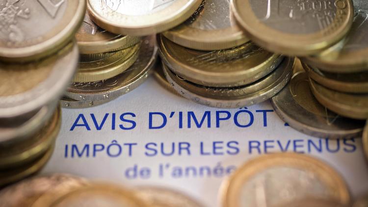 Un avis d'imposition sur le revenu et des pièces de 1 euro [Joël Saget / AFP/Archives]