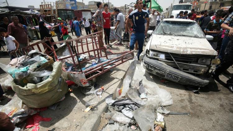 Des passants constatent les dégâts après l'explosion d'une voiture piégée près d'un marché du grand quartier chiite Sadr City, dans le nord de Bagdad le 11 mai 2016 [AHMAD AL-RUBAYE / AFP]