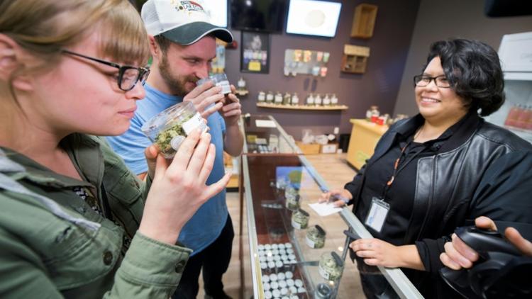 Des touristes venus de d'Arizona sentent des têtes de cannabis dans un magasin de Desert Hot Springs, en Californie, le 1er janvier 2018. [Robyn Beck / AFP]