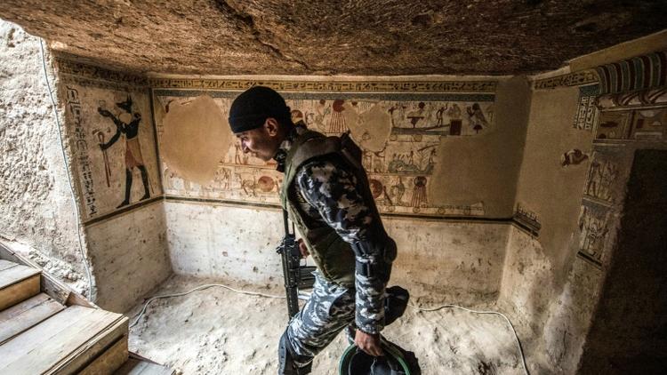 Un membre des forces de sécurité égyptiennes à l'entrée d'une tombe datant de 2.000 ans dévoilée le 5 avril 2019 à Akhmim [Khaled DESOUKI / AFP]