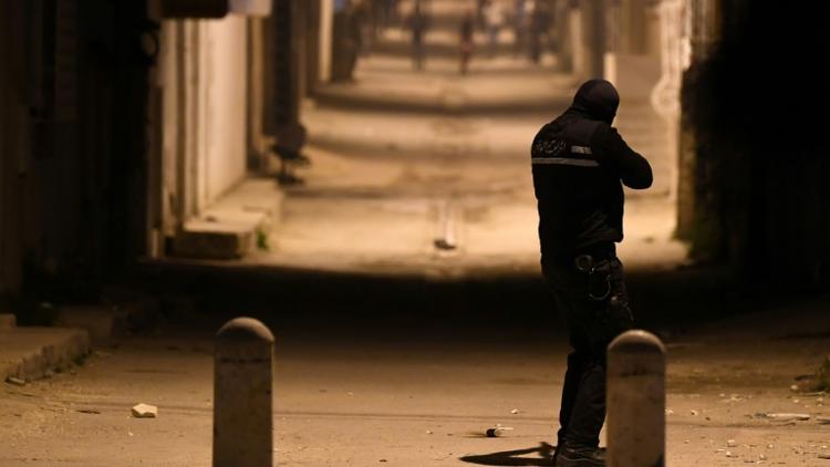 Un membre des forces de sécurité tunisiennes fait face à des protestataires dans le quartier d'Ettadhamen, en banlieue de Tunis, le 10 janvier 2018 au soir [FETHI BELAID / AFP]