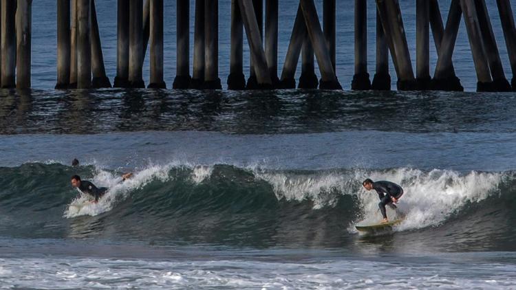 Des surfeurs près de la jetée d'Huntington Beach, le 2 mars 2020 en Californie [Apu GOMES / AFP]
