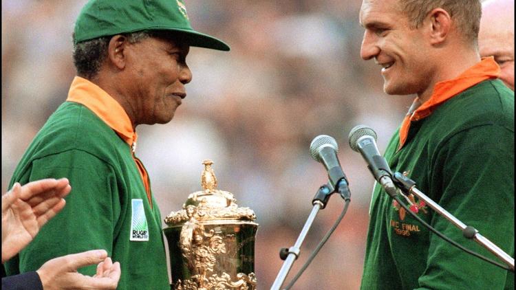 Nelson Mandela félicite le capitaine de l'équipe de rugby sud-africaine, François Pienaar, en lui remettant la coupe du monde de rugby, le 24 juin 1995 à Johannesburg [ / AFP/Archives]