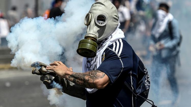 Un opposant vénézuélien porte un masque à gaz lors de heurts avec la police, le 6 avril 2017 à Caracas [JUAN BARRETO / AFP]