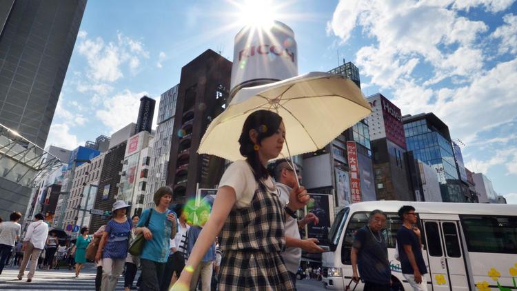 Des piétons utilisent des parapluies pour se protéger du soleil, le 11 juillet 2014 à Tokyo [Yoshikazu Tsuno / AFP]