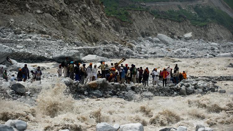 Des pèlerins attendent sur la rive d'un fleuve en furie d'être secourus, le 23 juin 2013 à Govindghat, en Inde [Manan Vatsyayana / AFP]