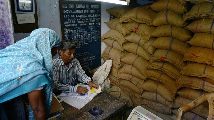 Le magasinier indien Brij Kishore (d) traite la carte de rationnement d'une cliente d'un dispensaire gouvernemental à Delhi le 10 juillet 2013 [Roberto Schmidt / AFP/Archives]