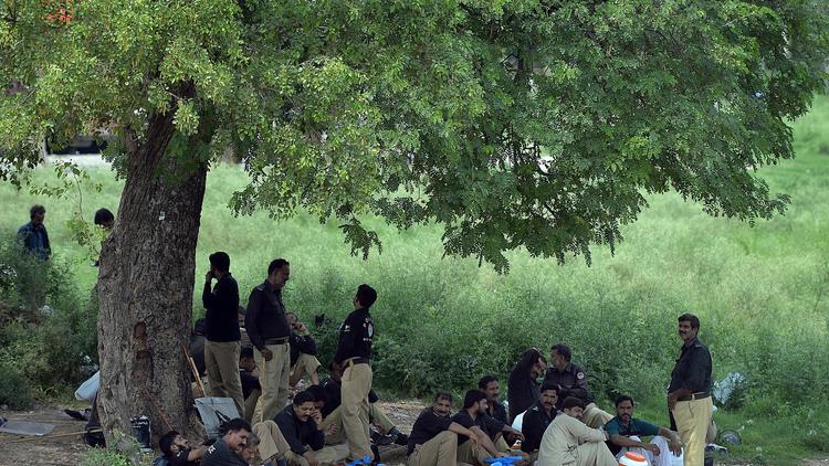 Des policiers pakistanais se reposent à l'ombre d'un arbre à Islamabad le 13 août 2014, où la situaiton est tendue à la veille de manifestations de l'opposition  [Aamir Qureshi / AFP]
