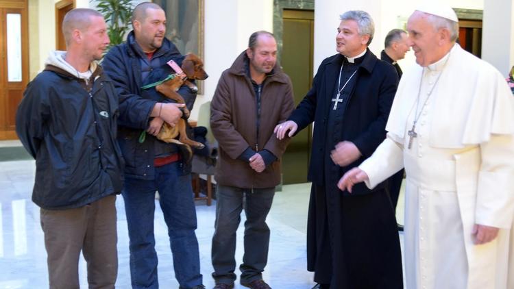 Photo publiée le 17 décembre 2013 par le service de presse du Vatican montrant le pape François (d) qui s'entretient avec trois SDF au Vatican [- / Osservatore Romano/AFP]