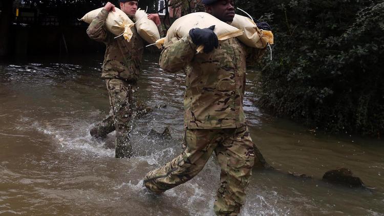 Des militaires transportent des sacs de sable pour protéger des habitations menacées par des inondations, le 14 février 2014 à Gloucester [Geoff Caddick / AFP]