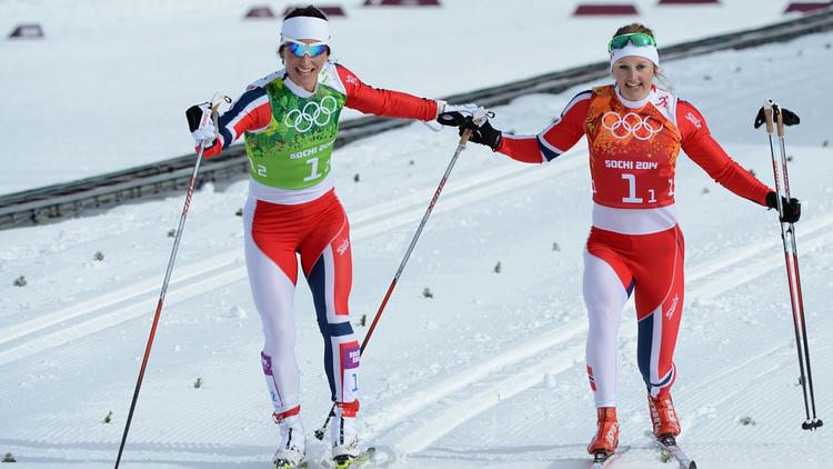 Les Norvégiennes Marit Bjoergen (g) et Ingvild Flugstad Oestberg franchissent la ligne d'arrivée après l'épreuve de cross-country par équipes, le 19 février 2014 à Rosa Khoutor [ / AFP]