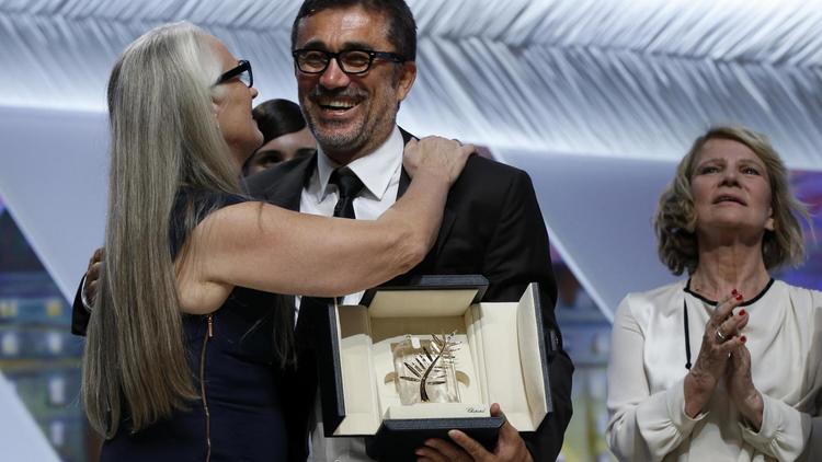 Le réalisateur turc Nuri Bilge Ceylan (c) félicité par la présidente du jury, Jane Campion, après avoir reçu la palme d'Or au 67e festival de Cannes le 24 mai 2014 [Valery Hache / AFP]