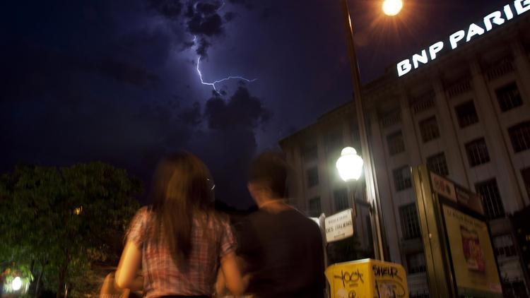 Une enseigne de la banque française BNP-Paribas  par une nuit d'orage le 8 juin 2014 à Paris [Pablo Porciuncula / AFP]