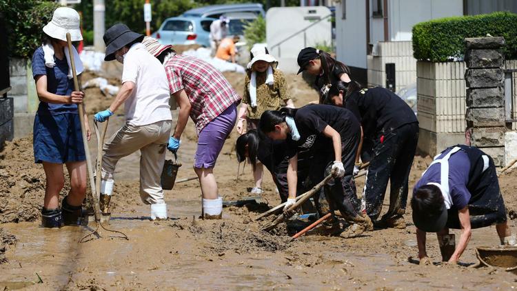 Des habitants enlèvent la boue de la route à Hiroshima le 21 août 2014 après des glissements de terrain  [ / Jiji Press/AFP]