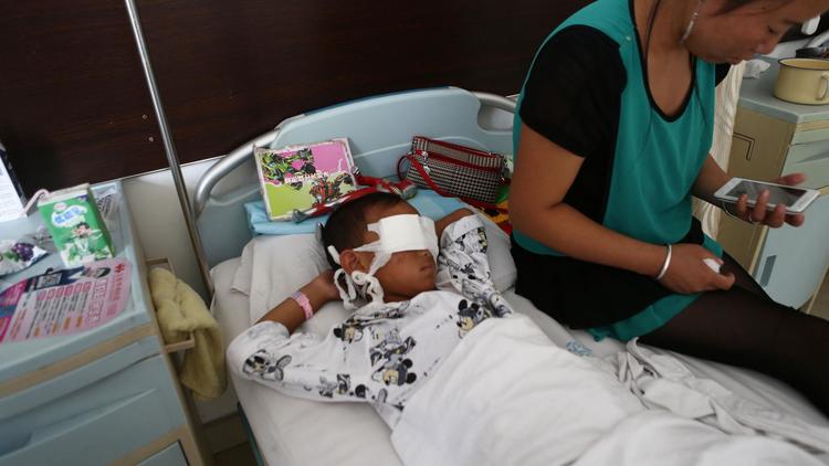 Un enfant qui a subi une double énucléation sur son lit d'hôpital à côté de sa mère, le 27 août 2013 à l'hôpital de Shanxi [- / AFP]