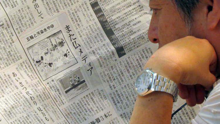 Un homme lit un journal local japonais parlant des deux illustrations du Canard Enchaîné, à Tokyo le 12 septembre 2013 [ / AFP]
