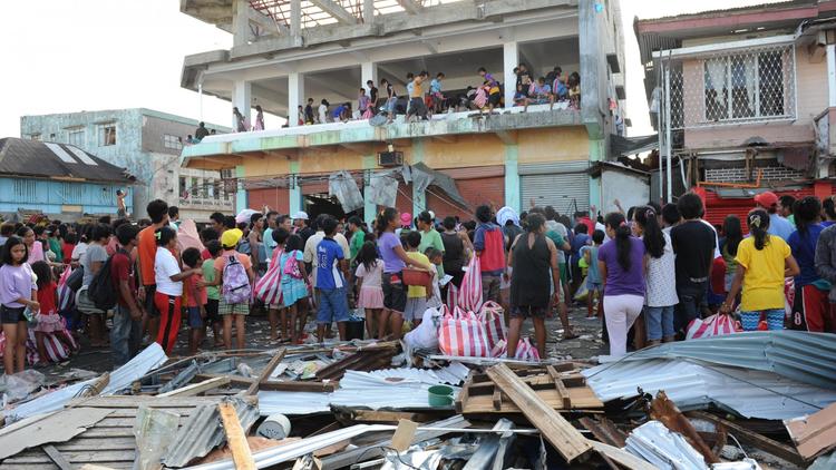 Des habitants de Guiuan en regardent d'autres occupés à piller un entrepôt, après le passage du typhon Haiyan, le 11 novembre 2013 [Ted Aljibe / Pool/AFP]