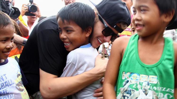 Justin Bieber serre dans ses bras un jeune rescapé du typhon Haiyan à Palo, le 10 décembre 2013 [ / AFP]