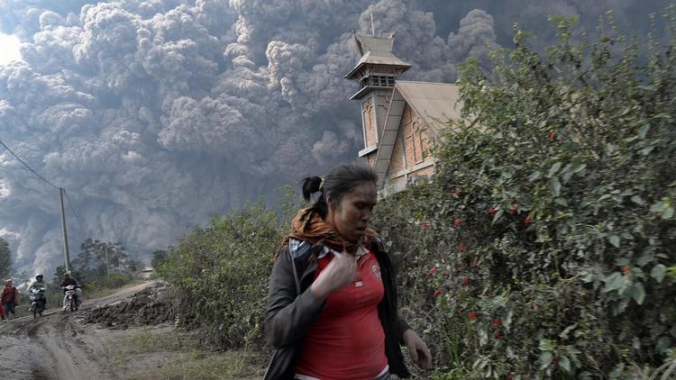 Une femme fuit l'éruption du volcan Sinabung (Sumatra Nord), le 1er février 2014   [Sutanta Aditya / AFP]